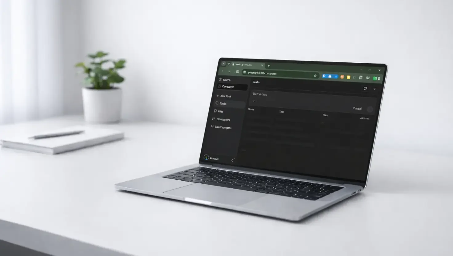 Silver laptop on a white desk, dark task-list interface open in a browser, pot plant and notebook behind.